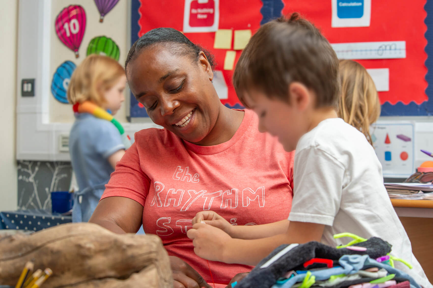 A teaching assistant talking to pupils in a classroom 